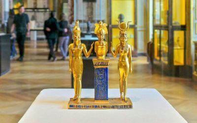 Golden ancient Egyptian statues displayed in a modern exhibition hall at NMEC Cairo